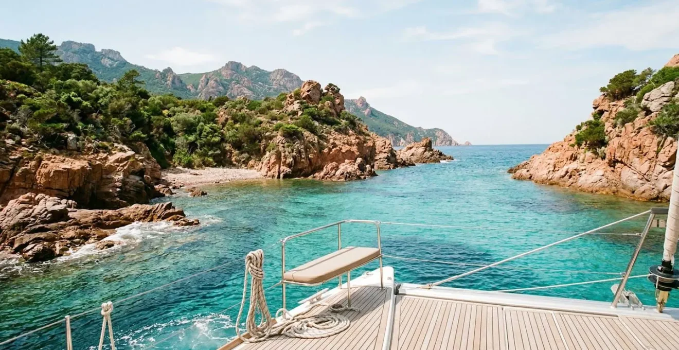 Crique isolée corse avec eau cristalline vue depuis un catamaran